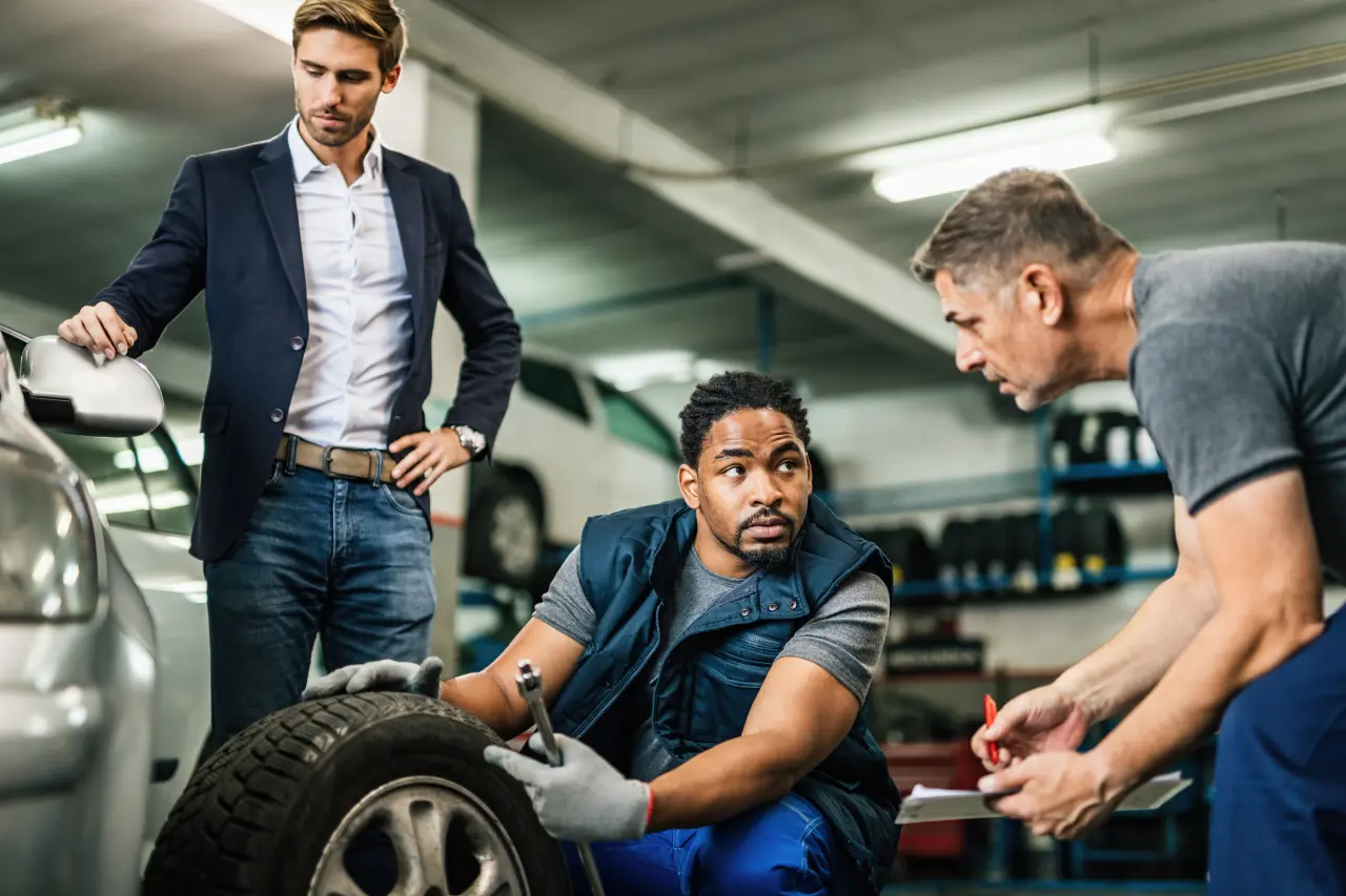 two-auto-mechanics-cooperating-while-repairing-tire-customer-s-car-auto-repair-shop